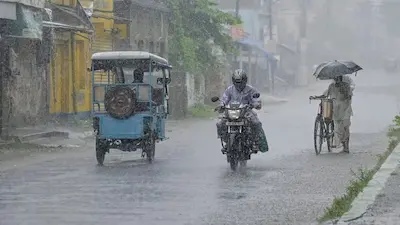 भारी बारिश के बीच जाते लोग.